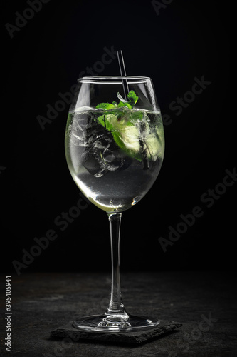Hugo cocktail with Prosecco, lime, ice, mint and Melissa syrup on a stone background, aperitif drink