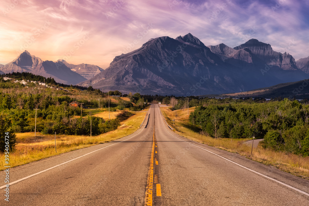 Beautiful View of Scenic Highway with American Rocky Mountain Landscape in the background. Colorful Summer Sunrise Sky. Taken in St Mary, Montana, United States. Beautiful View of Scenic Highway with American Rocky Mountain Landscape in the background. Colorful Summer Sunrise Sky. Taken in St Mary, Montana, United States.