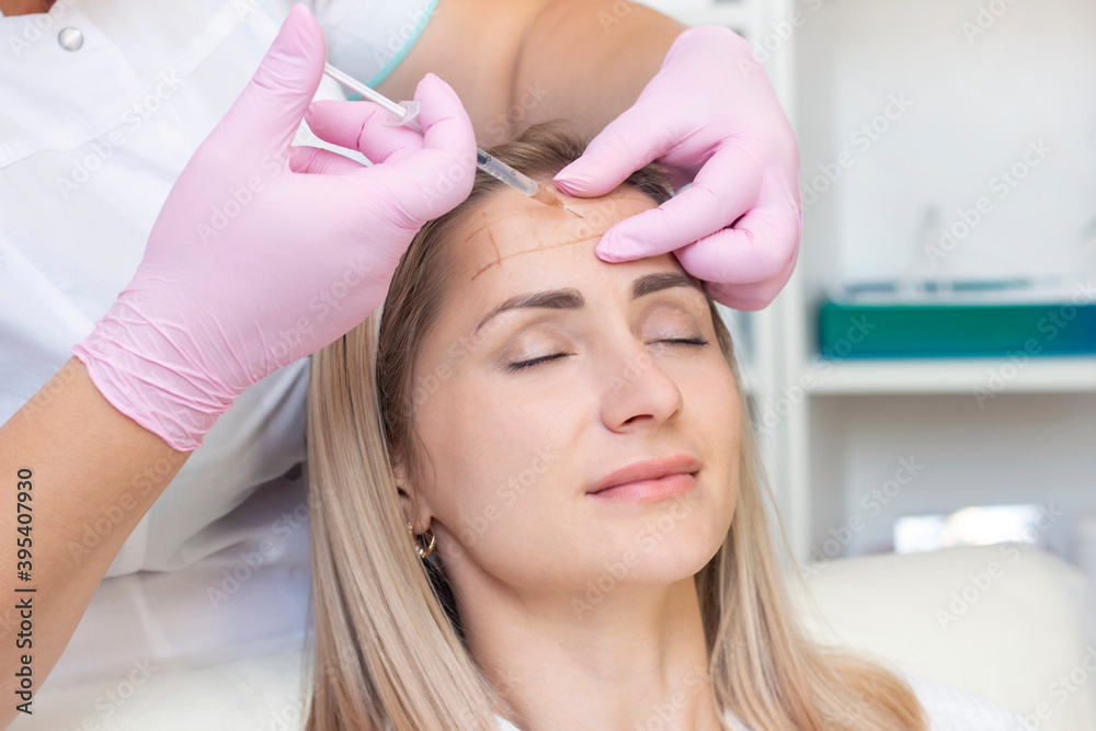 Naklejka premium young woman receiving cosmetic injection. Woman in a beauty salon. Plastic Surgery Clinic.