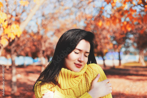 Young woman portrait in leaves. Hugging oneself happy and positive, smiling confident. Self love and self care
