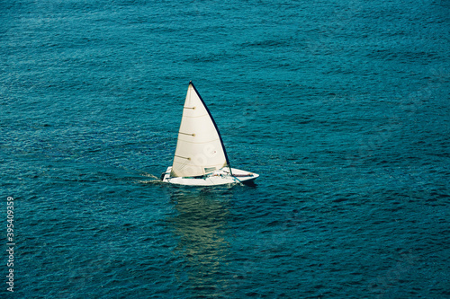 Sailing boat in open sea at sunlight. White sail on blue water. Luxury yacht in the ocean. Aerial view of Regatta sailing