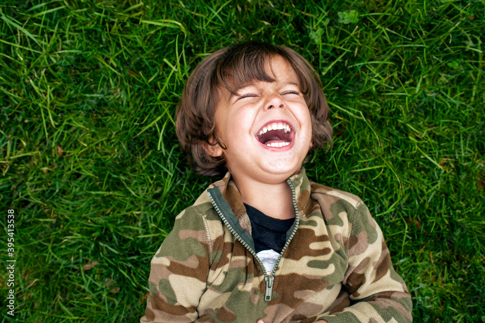 Little boy laughing on green grass