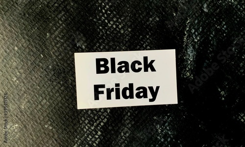 Black Friday on white paper on a black structural background.The concept of black Friday and discounts .