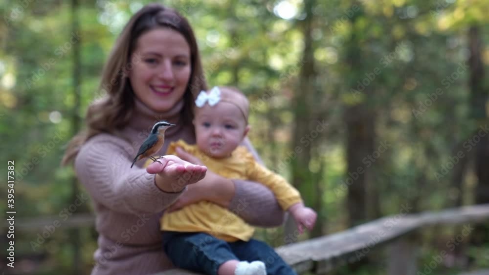Mother and her child girl in spring park with bird on hand Mother and her child girl in spring park with bird on hand