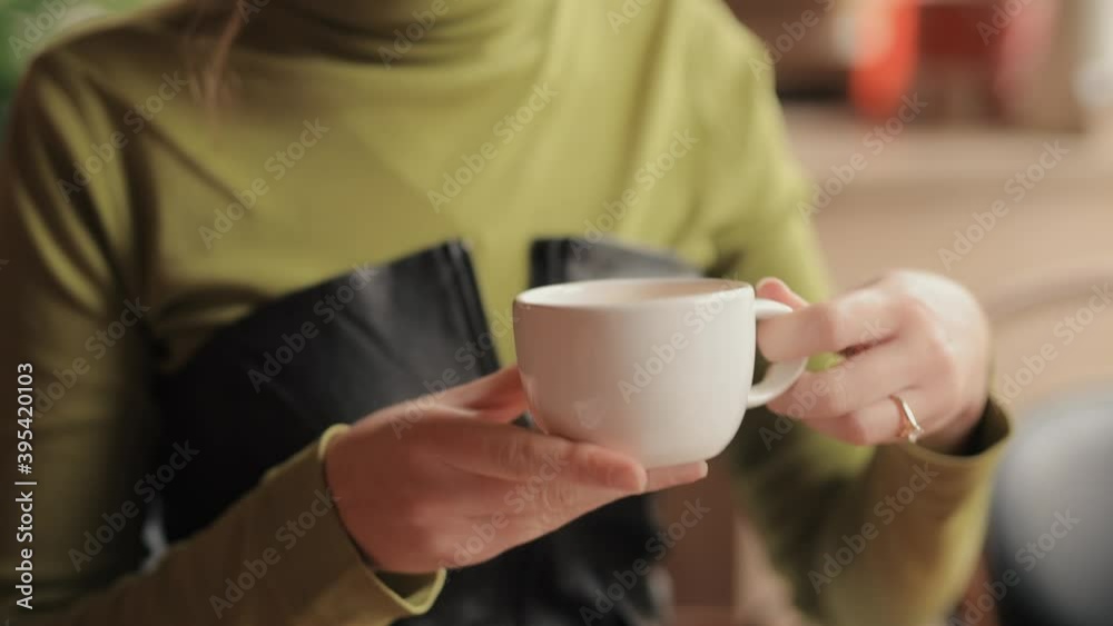 Young woman drinks a tea in the cafe with enjoyment Young woman drinks a tea in the cafe with enjoyment
