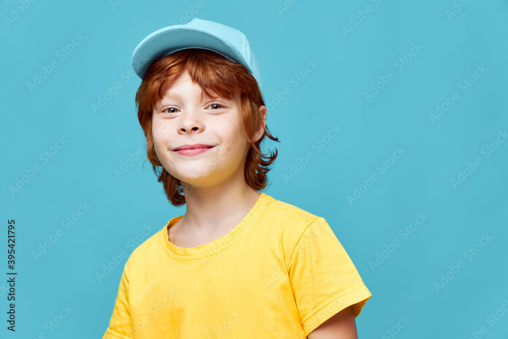 Portrait of red-haired boy yellow t-shirt blue cap isolated background Portrait of red-haired boy yellow t-shirt blue cap isolated background