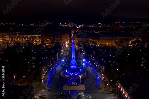 Riga,Latvia - 18 November 2020: Monument of freedom at night in Riga, Latvia during Staro Riga event. Milda - Statue of liberty holding three stars over the city illuminated in different colors. photo