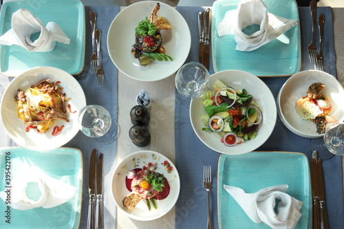 Served lunch in restaurant. Top view of tasty dishes are on the table. Beautifully served table for four persons in a restaurant.