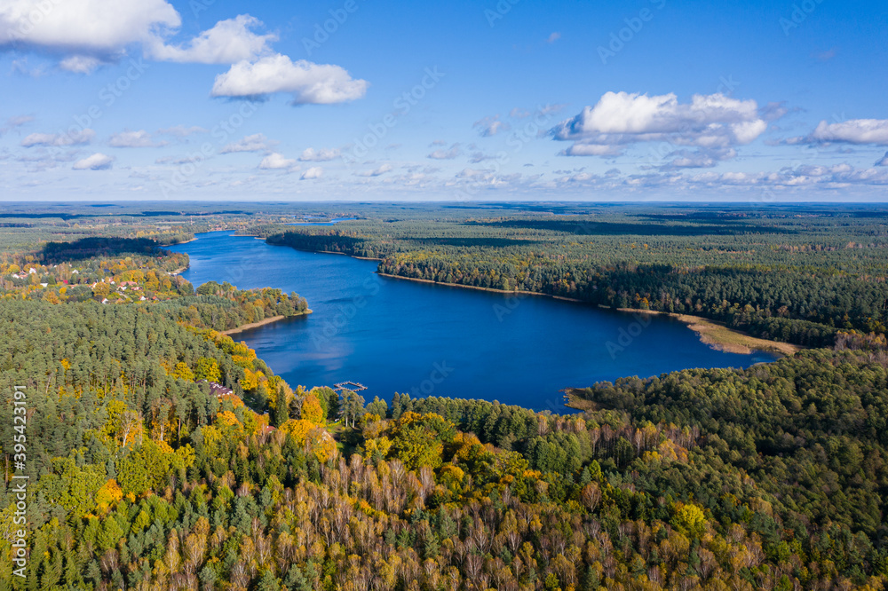 Aerial view of lake, autumn forest under blue cloudy sky