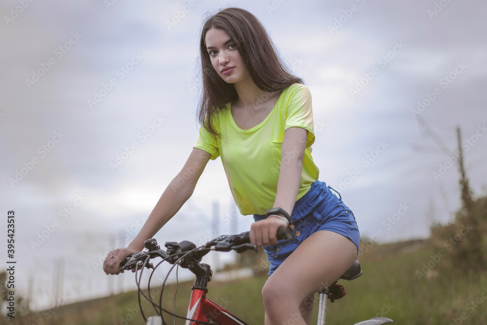 Fototapeta premium A girl in a t-shirt and shorts riding a bicycle