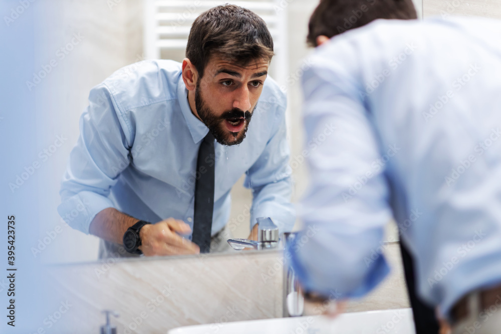Businessman washing his face in bathroom. Businessman washing his face in bathroom.