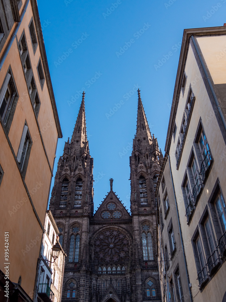 View on a street in Clermont-Ferrand. Gothic cathedral and French national monument located in the town of Clermont-Ferrand in the Auvergne, France. Blue sky and sunny day.