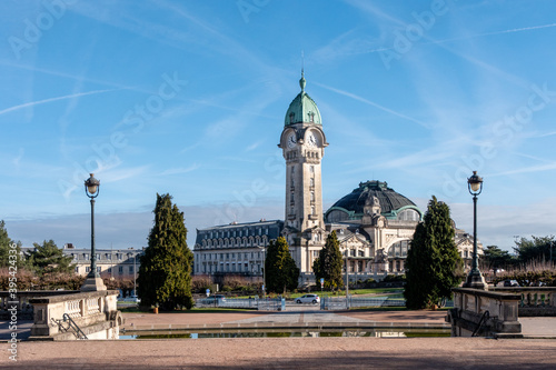 View on the Limoges train station, from a square. The station has a tower with a clock. Limoges is a city in the center of France. Sunny day, blue sky.