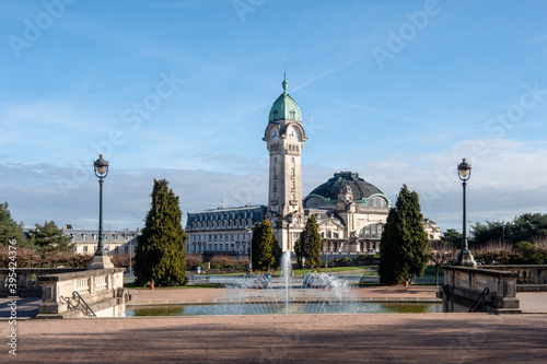 View on a park in Limoges. in the background there is the Limoges-Bénédictins train station (French: Gare de Limoges-Bénédictins). Lamp posts and fountain in the foreground. 