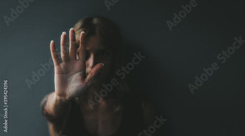 Stop violence against women! Woman raised her hand for dissuade standing against dark wall. 