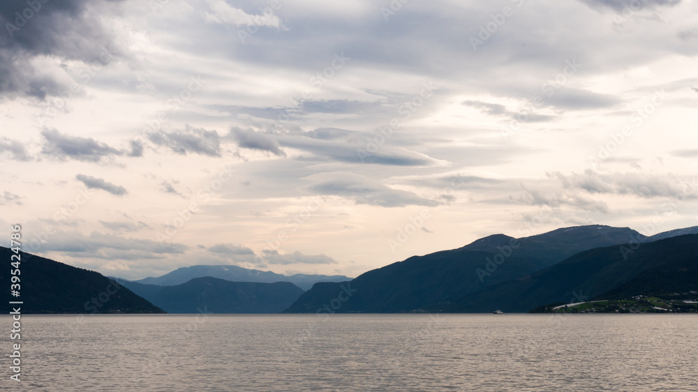 View on a Fjord in Norway, northern Europe, during a cruise north of the city of Bergen. Colorful skies, mountains on the sides. Photographed in summer. 