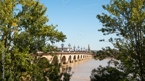 View on the Stone Bridge (Pont de pierre in french), behind the trees in the city of Bordeaux, in the south-west of France