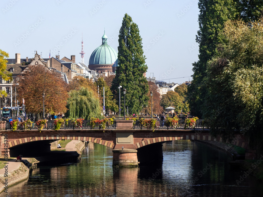 View on the Ill river in Strasborug, a city located in eastern France. In the background is the dome of the church of Saint-Pierre-le-Jeune in Strasbourg. Bridge in the foreground.