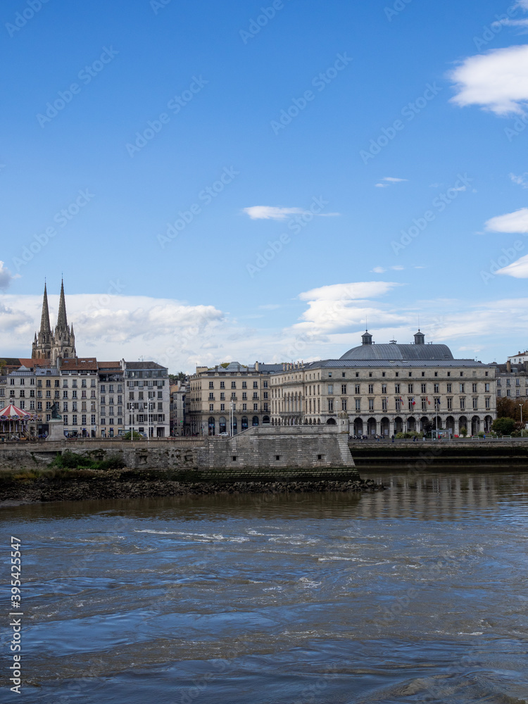 View on the Adour river in Bayonne, in southern France. Bayonne cathedral in the background. Blue sky. 
