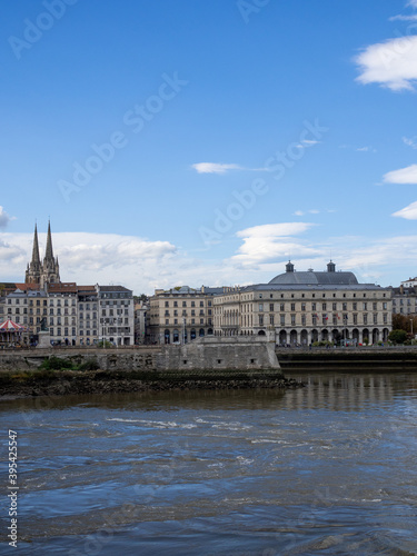 View on the Adour river in Bayonne, in southern France. Bayonne cathedral in the background. Blue sky. 
