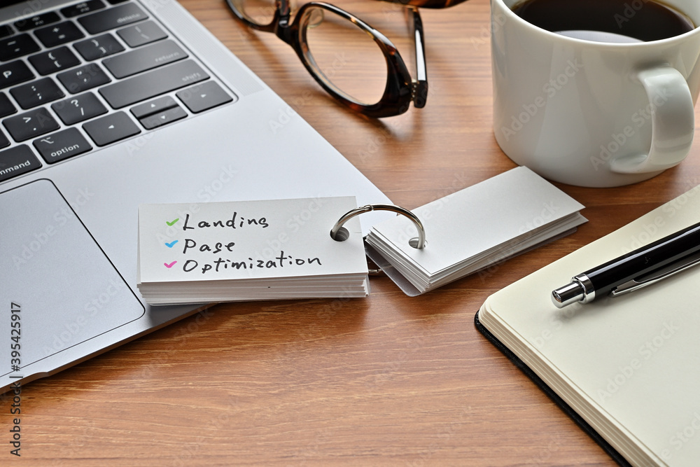 There is a piece of paper with a graph printed on it, a clipboard, and an open vocabulary book on the desk. There is the word Landing Page Optimization on it. There is a piece of paper with a graph printed on it, a clipboard, and an open vocabulary book on the desk. There is the word Landing Page Optimization on it.