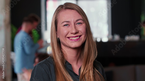 Portrait of attractive successful young blonde entrepreneur business woman cheerfully smiling at camera at trendy office