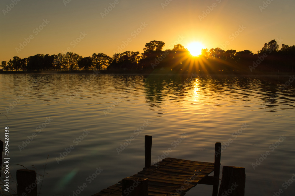  Sunset at Lobos lake, Buenos Aires. Taken from the shore looking to an old short wooden pier and the lake                                                     