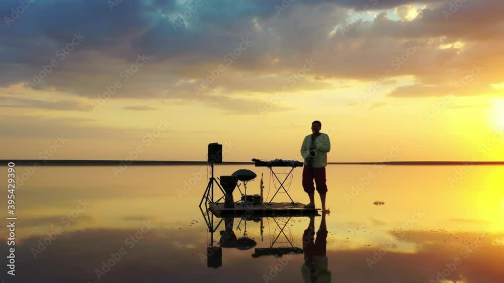 Stunning sunset in the background of a saxophonist on a small raft in the sea 4k Stunning sunset in the background of a saxophonist on a small raft in the sea 4k