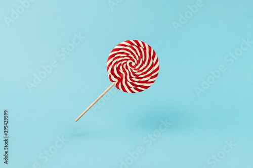 Colorful lolipop on blue background, wooden stick, red and white spiral, childhood sweets, Christmas concept photo