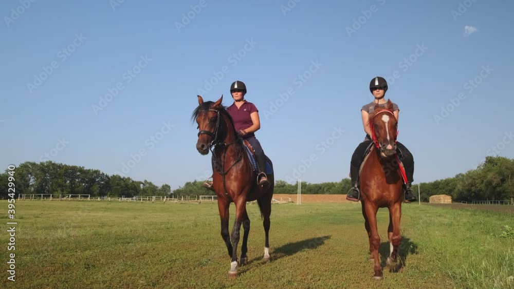 Two females are riding horses along country racetrack Two females are riding horses along country racetrack