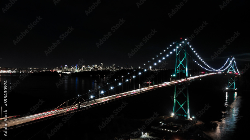 Lions Gate Bridge at night with downtown Vancouver, BC in the background.