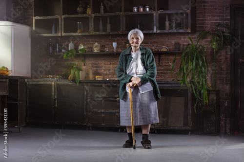 Fotografi Portrait of senior woman with walking stick at home