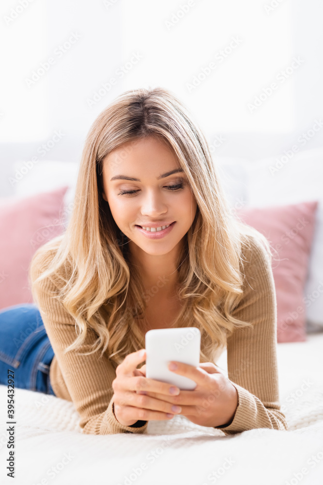 woman using smartphone while lying on bed woman using smartphone while lying on bed