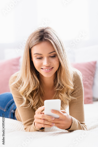  woman using smartphone while lying on bed