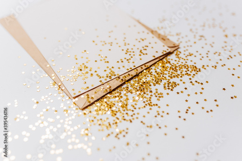 Blank note with envelope and gold glitter stars on white background