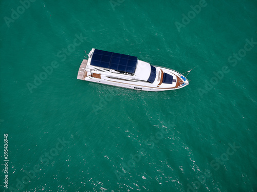 Aerial photo of an isolated luxury white yacht with blue roof design in the sea