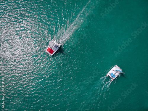 Two Sailing ship yachts with white sails and  red awning from the sun for passengers at open sea. Aerial - drone view to sailboat in windy condition © Semachkovsky 