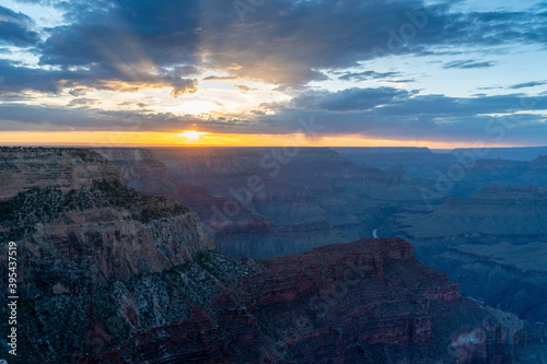 sunset shot of sunbeams extending upwards from behind clouds at hopi point of the grand canyon national park in arizona