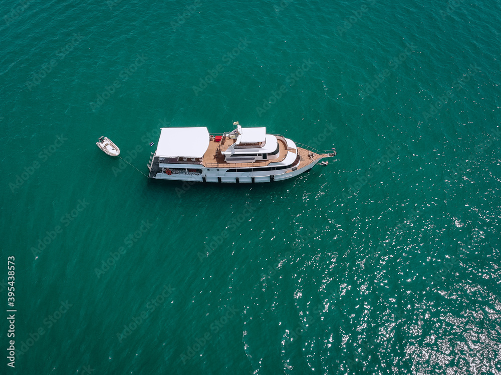 Aerial drone top view photo of luxury yacht with white rubber boat. Phuket. Thailand..