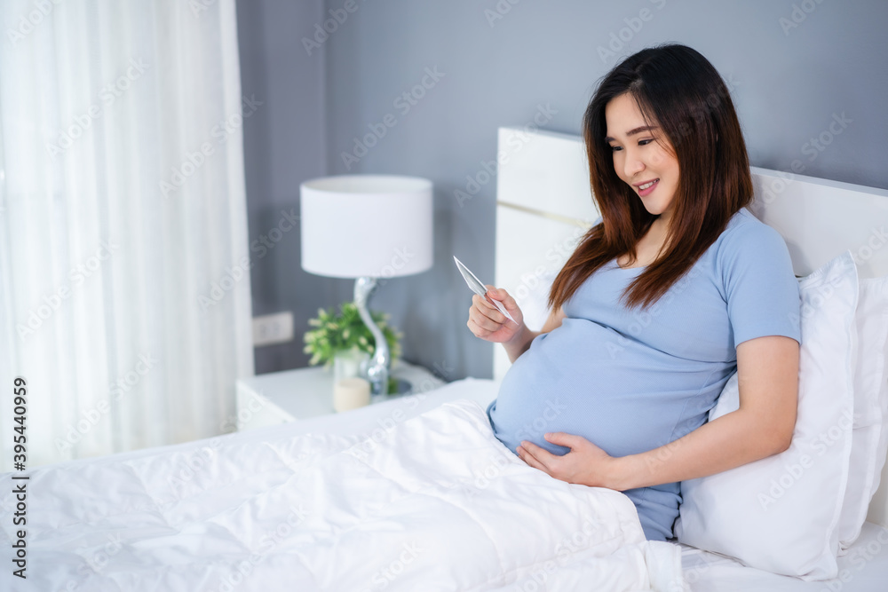 happy pregnant woman holding and looking ultrasound scan photo on bed happy pregnant woman holding and looking ultrasound scan photo on bed