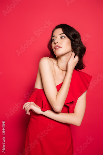  woman in red dress looking away on red background