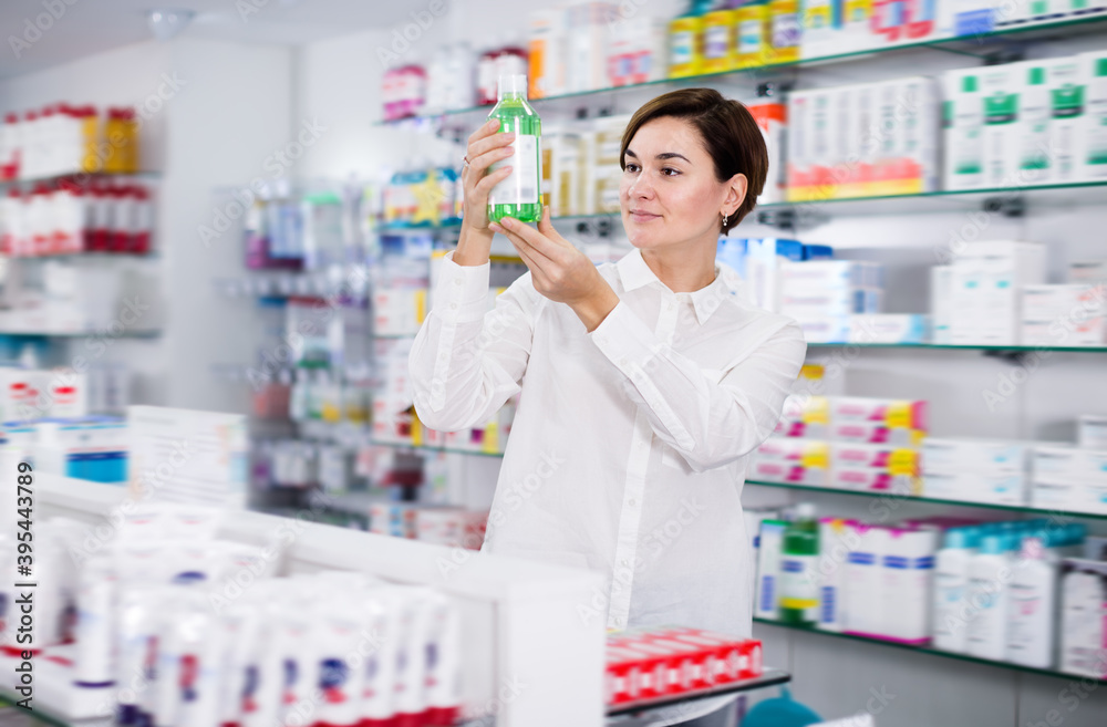 Adult woman customer browsing rows of drugs in pharmacy