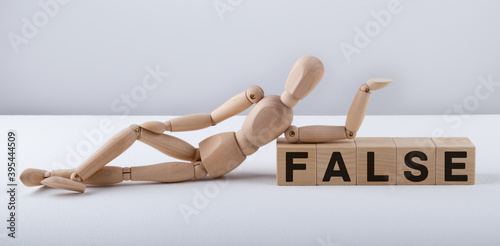 Wooden man sits on wooden cubes with the text FALSE.