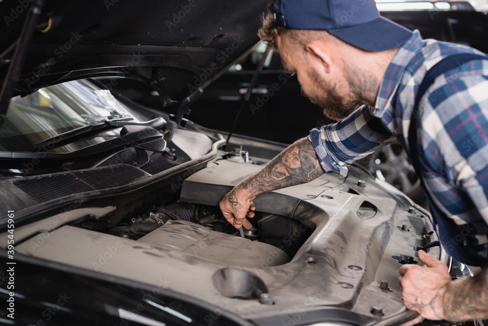 mechanic checking level of oil in car engine on blurred 