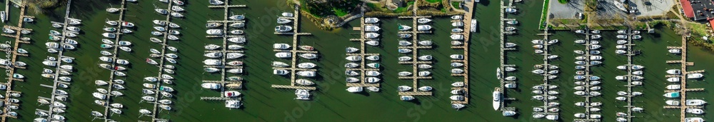 Fototapeta premium Aerial panorama of Deale waterfront docks on the Western Shore of Chesapeake Bay Maryland, with rows of of luxury sailboats docking in the marina. 