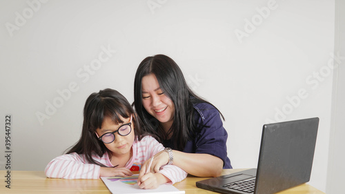 Covid-19 Coronavirus and Learning from home, Home school kid concept.Little asian girl study with online learning and asian mother work from home with laptop.Education and Social distancing concept.