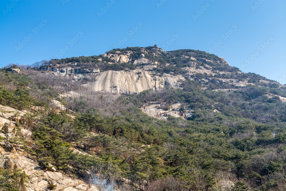 Peak of Bukhansan Mountain national park with rocks, snow, and dead trees in the spring in Seoul of South Korea.