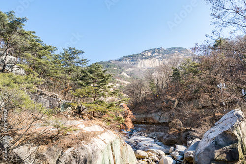 Peak of Bukhansan Mountain national park with rocks, snow, and dead trees in the spring in Seoul of South Korea. photo