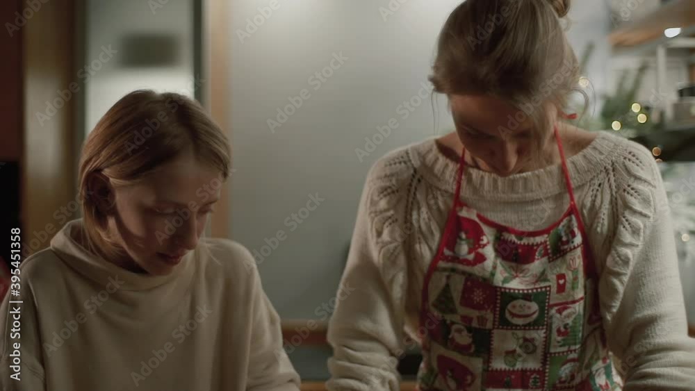 Beautiful Mom with a cute daughter are preparing pastries in the kitchen. Mom teaches her daughter to bake cookies. Cooking cookies for the New Year and Christmas holidays. Dough preparation Beautiful Mom with a cute daughter are preparing pastries in the kitchen. Mom teaches her daughter to bake cookies. Cooking cookies for the New Year and Christmas holidays. Dough preparation