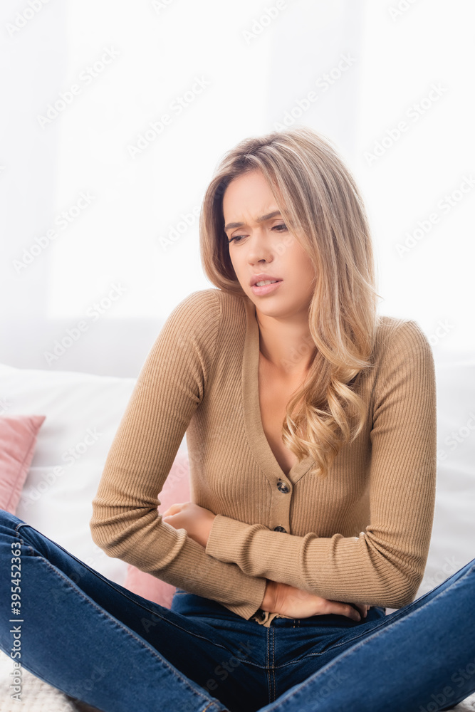  woman suffering from stomach pain on bed